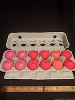 One dozen pink golf balls in original carton, showcasing mixture of brands including Titleist, Volvik and Callaway.