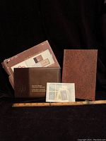 Full lot view showing outer box, stamp binder, cardboard booklet, and plastic sleeve with stamps alongside a ruler for scale.