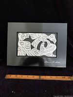 Full view of the rectangular wooden box showing black frame and white carved Haida art panel with signature