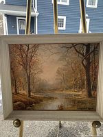 Front full view of the framed painting showing the autumn landscape, river, trees, and artist signature.