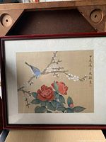 Full framed artwork showing a blue bird perched on blossoming branches with red flowers on silk fabric background.