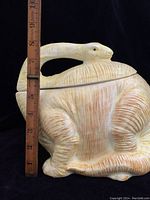 Side view of the yellow dinosaur cookie jar with a measuring ruler showing height approximately 8 inches.
