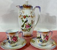 Full set showing chocolate pot and two tea cups on matching saucers with colorful peacock and floral decorations on lustreware porcelain.