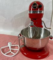 Front view of Empire Red KitchenAid Professional 5 Plus stand mixer with bowl and whisk on pink surface