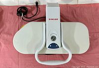 Singer heat press viewed from above showing white body, handle, and power cord