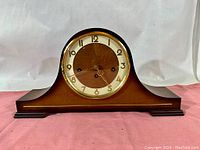 Front view of the wooden Ergo mantel clock showing clock face and full base with curved contours.