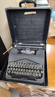 Full view of antique portable typewriter inside its open black carrying case.