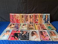 Wide shot of 18 assorted vintage Cosmopolitan magazines laid out in rows showing full covers