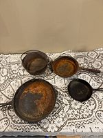 Overview of all five cast iron pieces displayed on lace-covered table