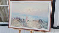 Framed oil painting of two girls in a flower field, with pastel colors and signature visible
