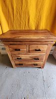 Front view of solid cherry 4 drawer dresser with visible wood grain and black metal handles on drawers.