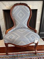 Front view of walnut parlour chair showing carved rose crest, balloon back and upholstered seat.