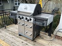 Full view of stainless steel Broil King barbecue with side shelves and control knobs
