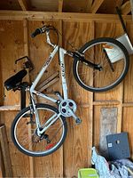Full side view of the bicycle hanging on a wooden wall showing frame, wheels, drivetrain and seat.