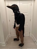 Full costume view worn showing loon bird head, tailcoat jacket, brown pants, and bird feet.