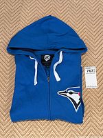 Blue Jays blue zip-up hoodie sweatshirt folded showing the front with large embroidered Blue Jays bird logo on left chest area.