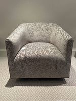 Front-facing view of chair showing curved arms, geometric pattern and seat cushion