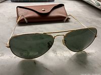 Angled front view of sunglasses resting on table in front of open brown case