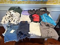 Overall view of fourteen mixed women's clothing items on white table