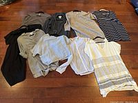 Eight garments arranged on hardwood floor for overview