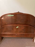 Photo showing antique wooden headboard and footboard with carved details and polished finish.