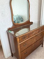 Side angle showing full dresser with attached large mirror and smooth wooden finish.