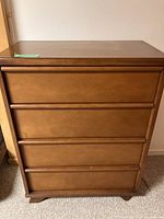 Front view of the dresser showing all 4 drawers closed with integrated handles and light brown finish.