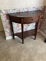 Front view of the half-circle solid wood hall table with a drawer showing the woven cane front and turned legs.