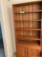 Full frontal view of the wooden bookcase showing five shelves and the two-door cabinet below.