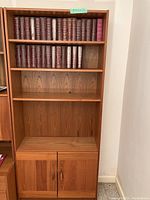 Full view of the bookcase showing four shelves and lower cabinet with two doors, wooden construction with medium brown finish and visible grain.