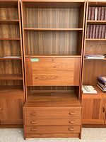 Front view of the entire wooden cabinet featuring bookshelves, a drop-front door, and three drawers.
