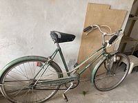 Side view of a green vintage CCM Elan pedal bike showing the frame, tires, and saddle