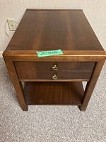 Front view of one side table showing drawer with metal pulls and lower shelf, finished in dark wood.