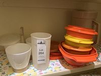 Vintage Tupperware containers including condiment containers with colorful lids and an opaque white plastic cup.