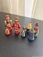 Photo showing seven handpainted Russian inspired wooden chess pieces including king, queen, pawns, knight, and rook.