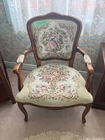 Front view of wooden Victorian armchair with tapestry upholstery showing floral seat design and figurative backrest panel