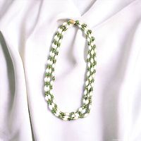 Full view of the three-strand necklace on white silk fabric background showing the combination of pearls, jade beads, and gold spacers.