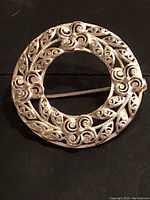 Front view of circular vintage Birks filigree sterling silver brooch showing detailed scroll and leaf design.