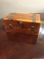 Front angled view showing wood grain, brass latch, and decorative brass plates.