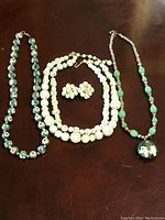 Overview of all items including two cloisonne necklaces and the pastel green beaded necklace with matching earrings laid out on a surface.