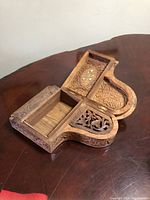 Open hinged piano shaped trinket box showing carved compartments and mother-of-pearl inlay on the lid