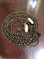 Five strand beaded necklace with dark faceted beads and a strong clasp, shown coiled on a wooden surface.