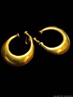 Pair of crescent-shaped gold plated earrings shown against a black background to highlight shape and color.