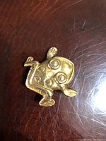 Top view of signed gold plated frog brooch showing stylized design and circular motifs on its back