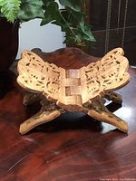 Front angled view of hand carved vintage wooden folding book rest showing intricate openwork pattern and folding hinge.