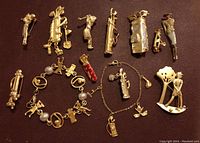 Full view of all gold-tone golf-themed brooches and charm bracelets arranged on brown leather surface.