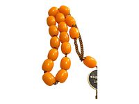 Photo of the orange oval bead strand showing chain link connections and the black and gold medallion inscribed with 'Epirotiki Lines' attached with a gold chain tassel.