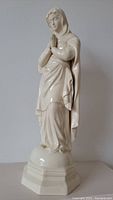 Front view of full figurine showing praying hands and draped robes