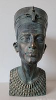 Front view of resin bust depicting Queen Nefertiti with aged bronze patina showing detailed facial features, necklace, and headdress with uraeus.