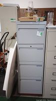 Full front view of the closed file cabinet showing four drawers and a lock on the second drawer.